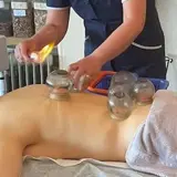 Traditional Chinese cupping therapy with glass cups placed on a patient's back to promote circulation and relieve muscle tension.